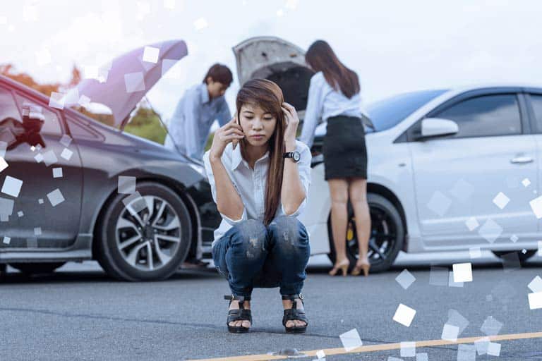 Woman making a call with a car accident at the background.